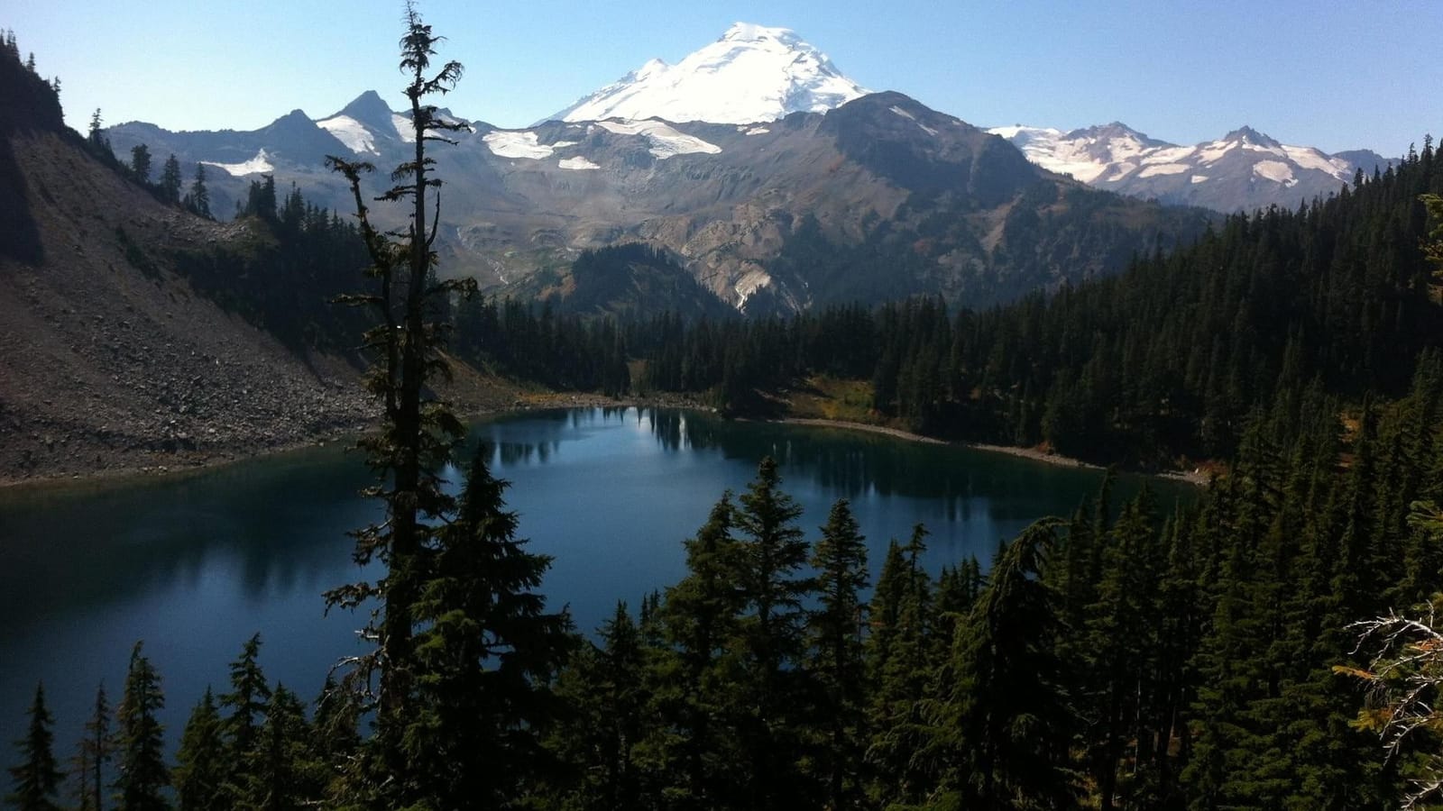 Iceberg Lake on the Chain Lakes Loop, with snowy Mt. Baker above forested ridges