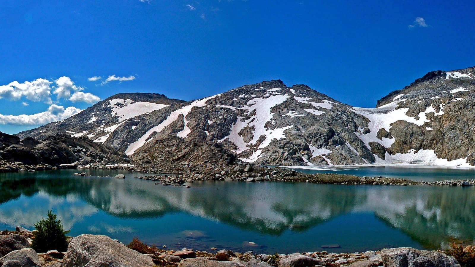 A still alpine lake in the Enchantments reflecting snow-streaked granite peaks