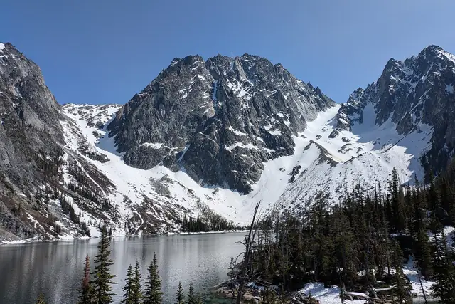 Dragontail Peak still deep in snow above a partly frozen Colchuck Lake in late May