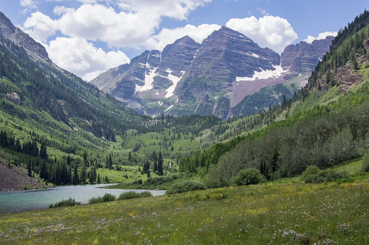 The Maroon Bells above Maroon Lake and green meadows in August