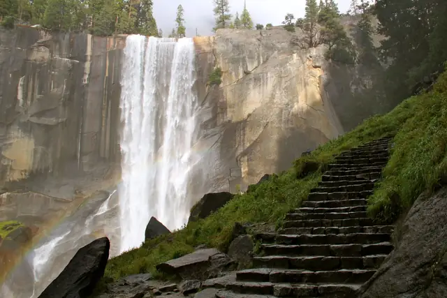 Granite steps of the Mist Trail climbing beside Vernal Fall, with a rainbow in the spray