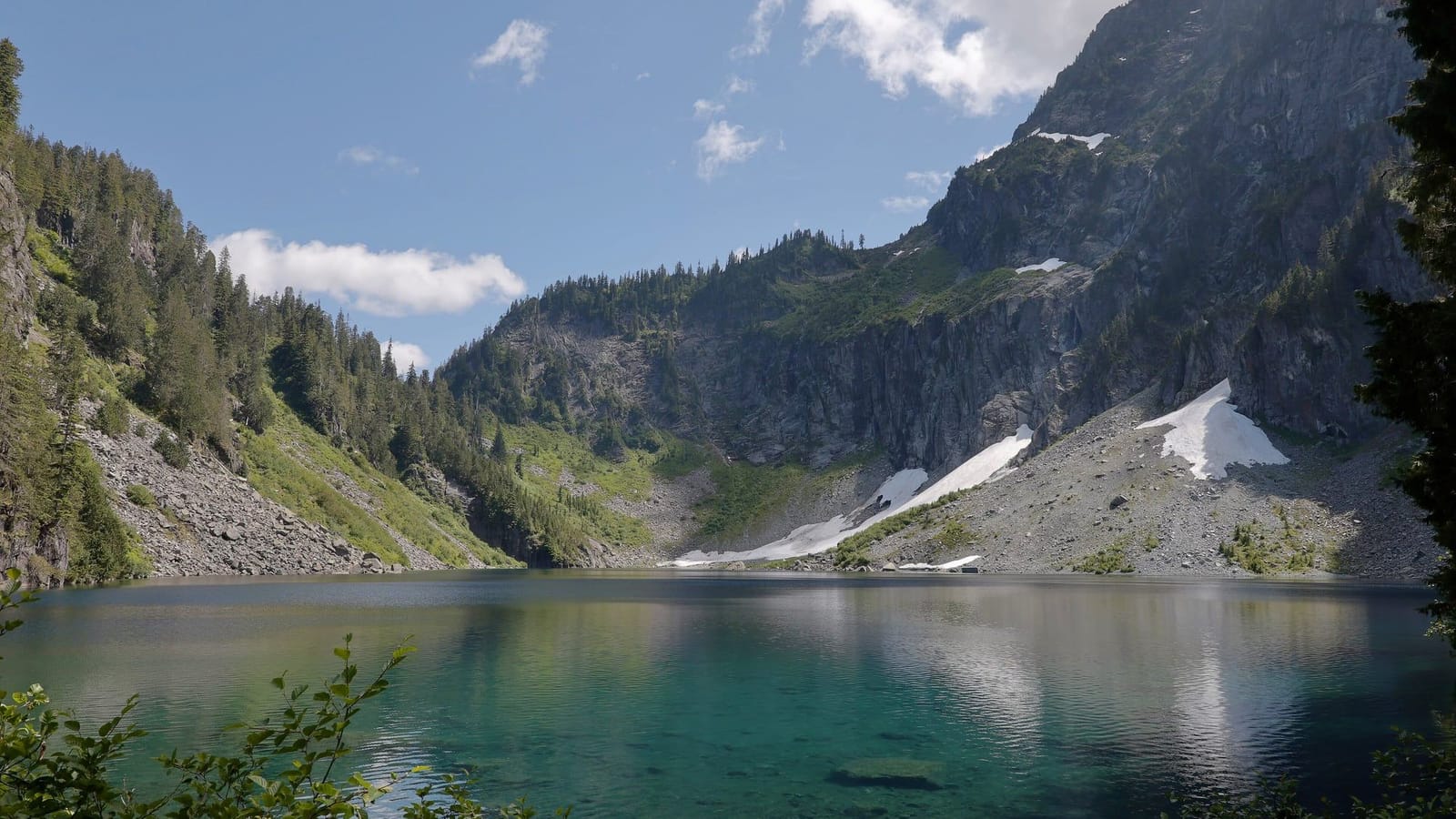 Blue-green Lake Serene below the cliffs of Mt. Index, with lingering snow patches