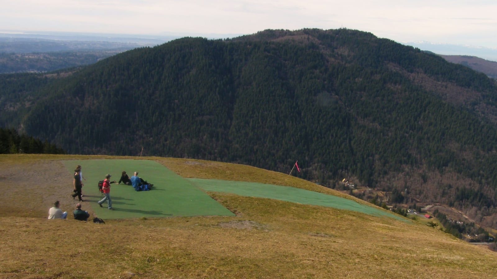 The grassy paraglider launch at Poo Poo Point looking out over forested foothills